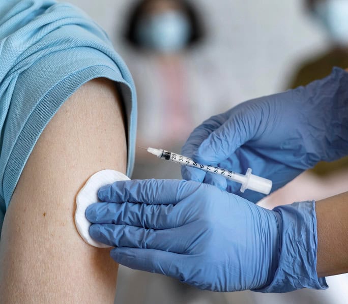 Healthcare professional administering COVID-19 vaccine injection in arm.