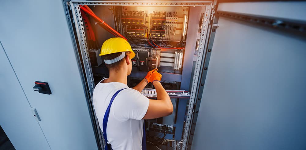 Electrical technician working on medical equipment control panel.