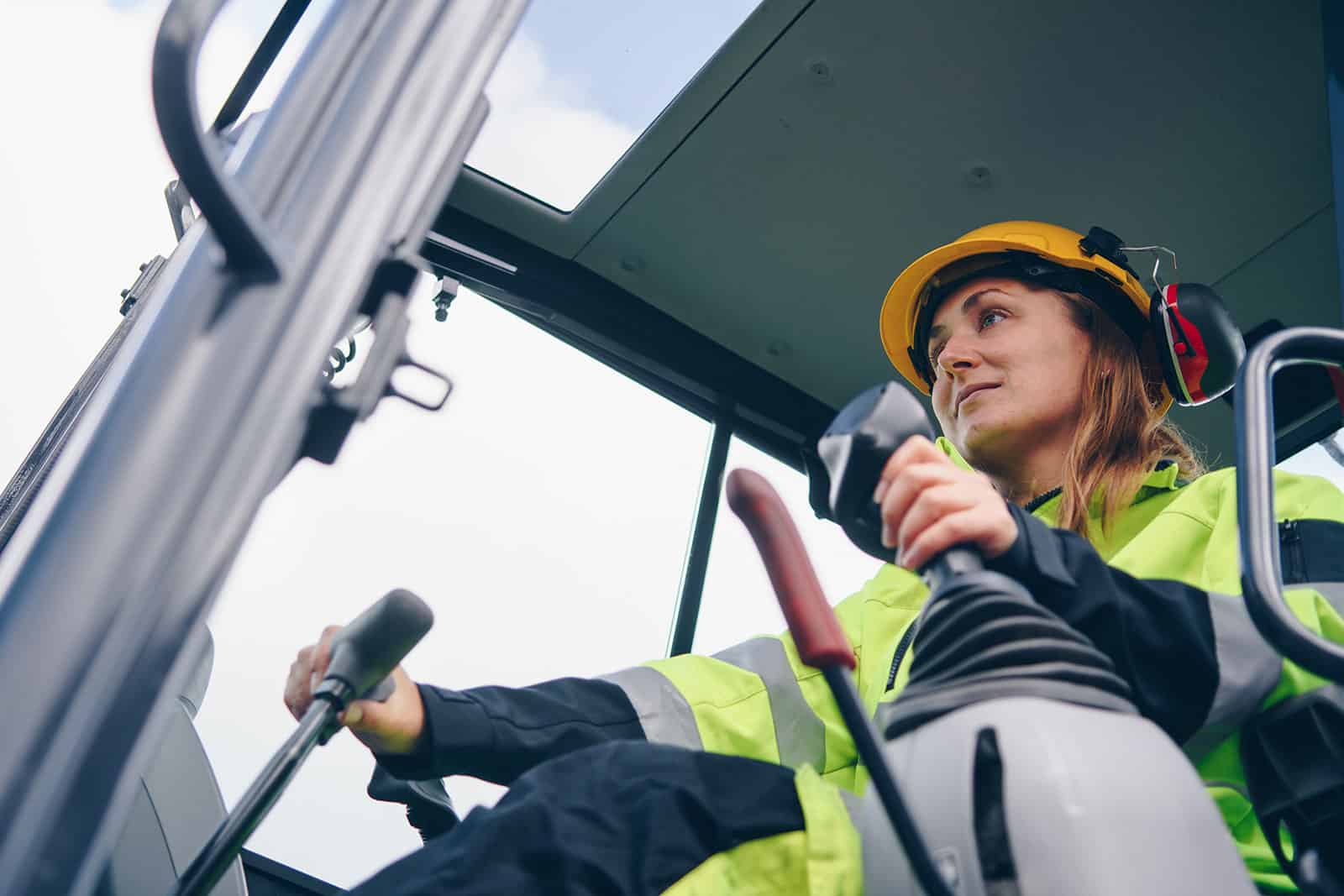 Construction machinery operator wearing safety gear on a building site.