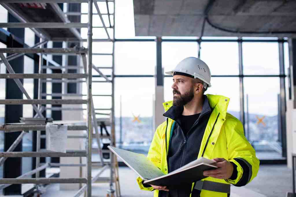 Construction worker in safety gear inspecting site health and safety measures.