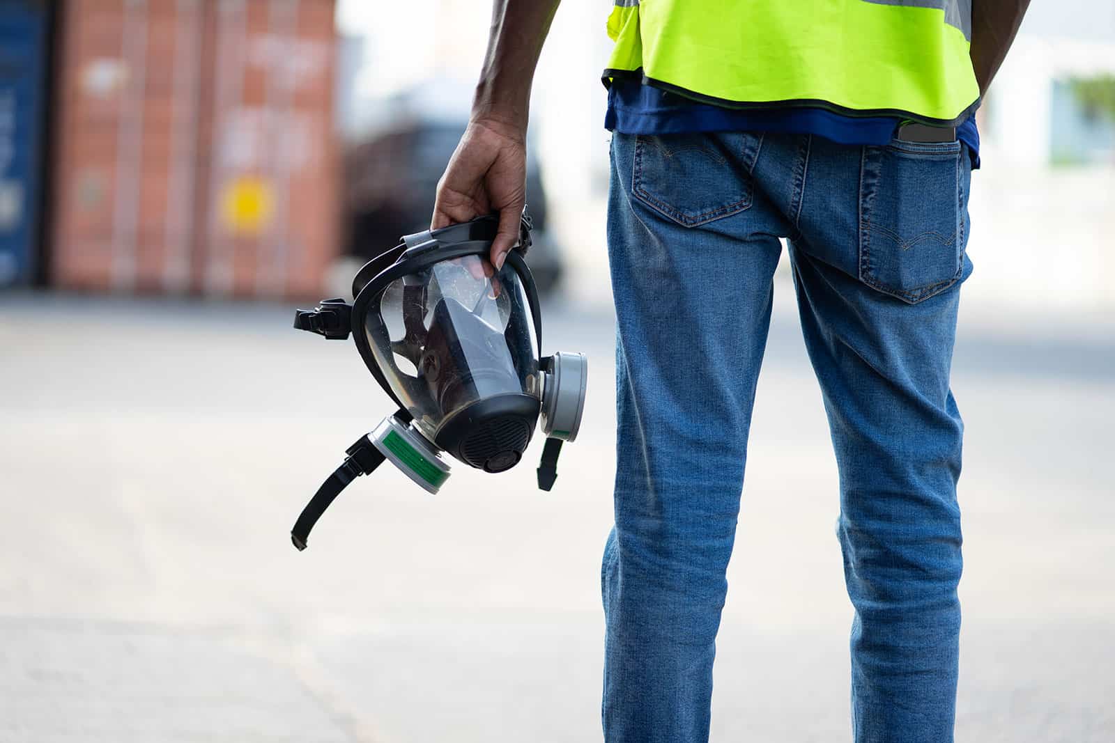 Person holding a face fit testing mask in an industrial setting.