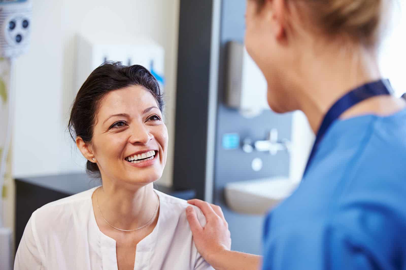 Female patient smiling during consultation with healthcare professional.