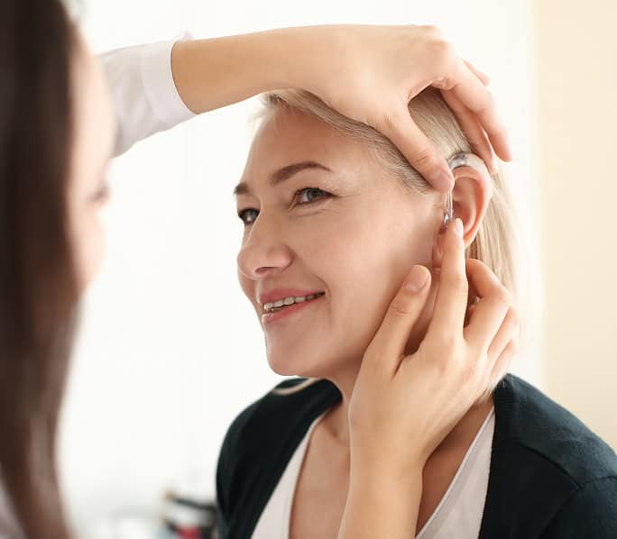 Audiologist performing a hearing test on a woman at NHS Audiology.