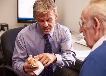 Audiologist explaining hearing aid options to an elderly patient.
