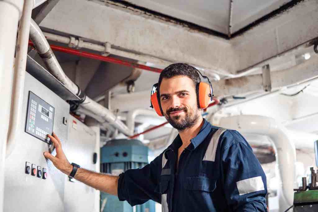 Offshore medicals technician using control panel in industrial environment.