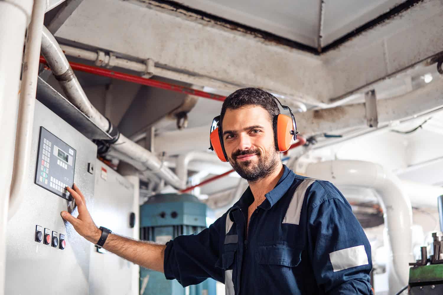 Offshore medicals technician using control panel in industrial environment.
