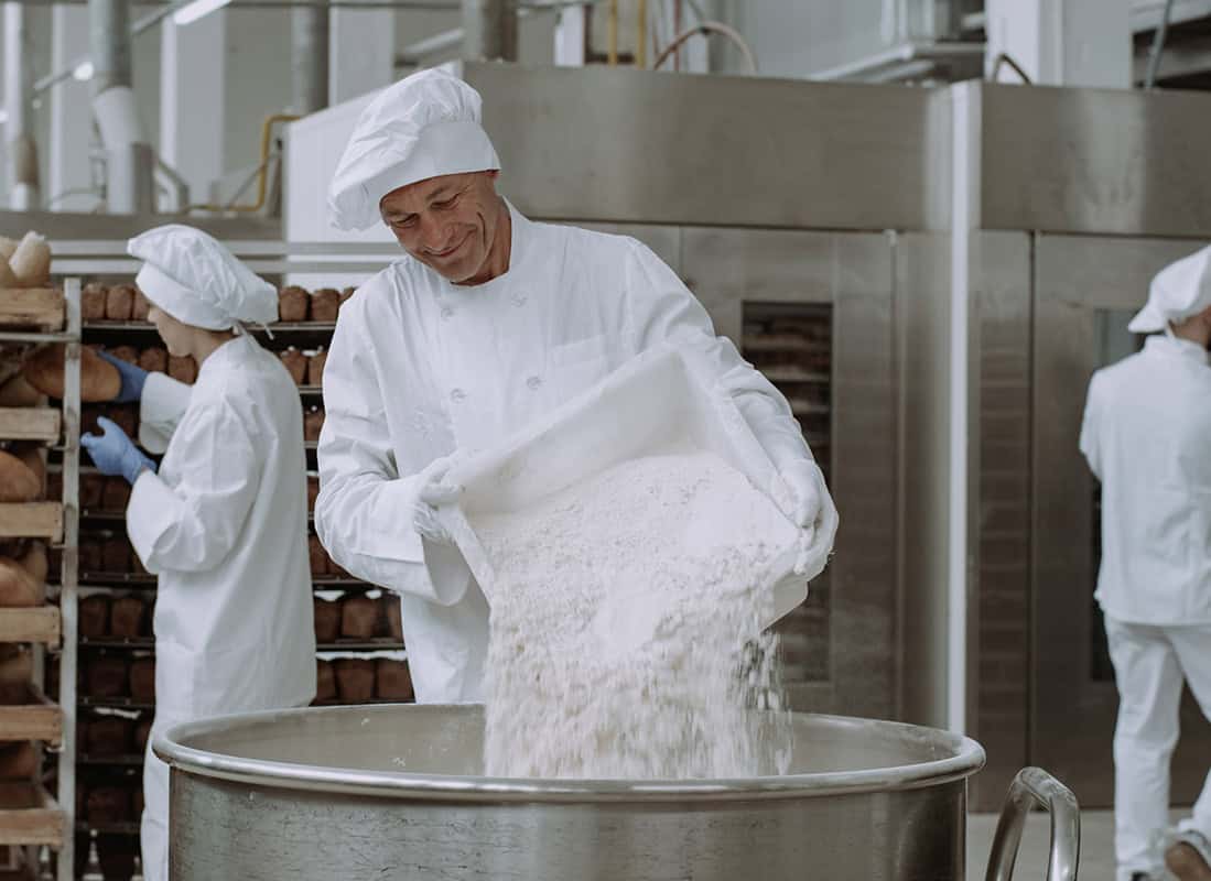 Food production worker handling ingredients in a food manufacturing facility.