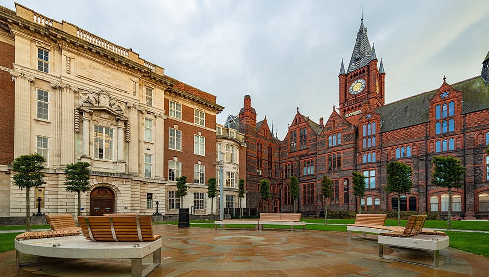 Historic university building with clock tower in a city square.