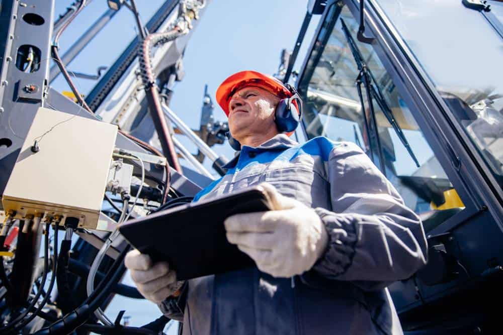 Offshore worker with safety gear inspecting equipment at sea.