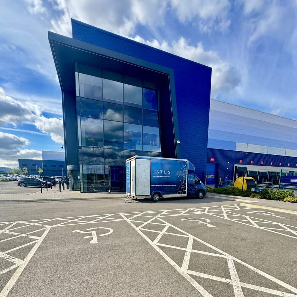 Modern blue LATUS Group building with glass facade and parking lot.