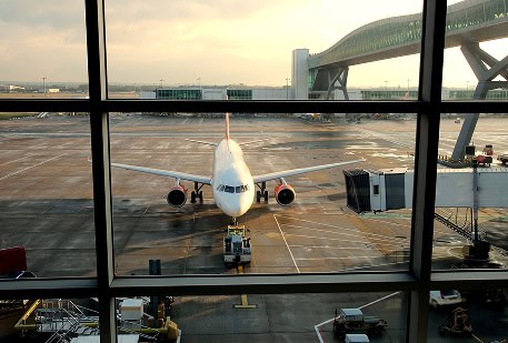Airplane parked at gate in a busy airport terminal, ready for passenger boarding.