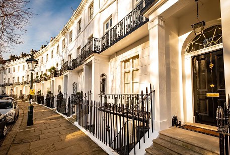Modern white office building with black railings on a sunny street.