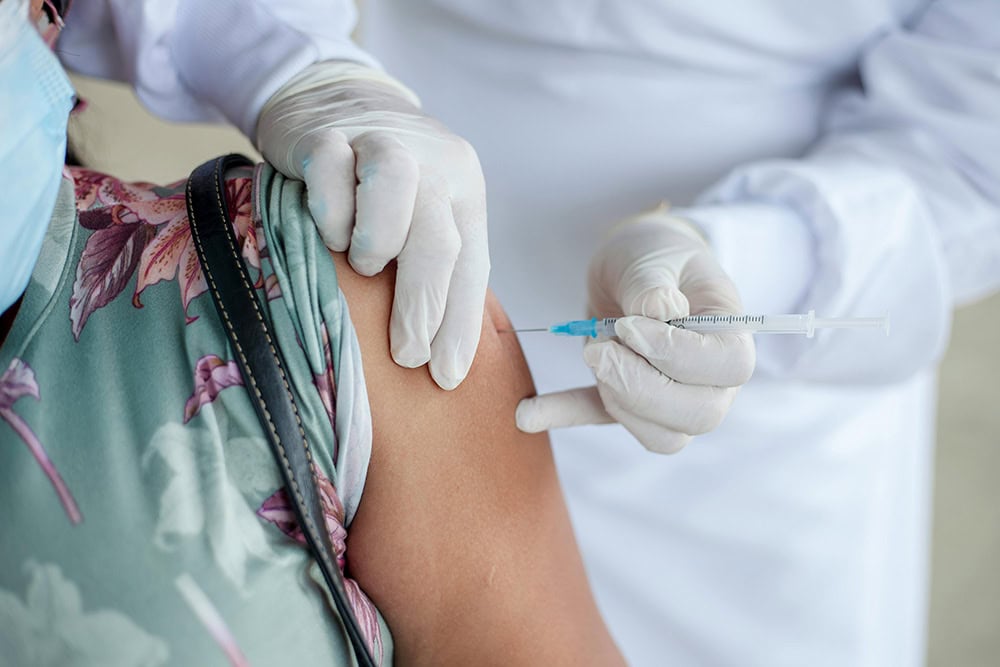 Healthcare professional administering a vaccine to a student in a clinical setting.
