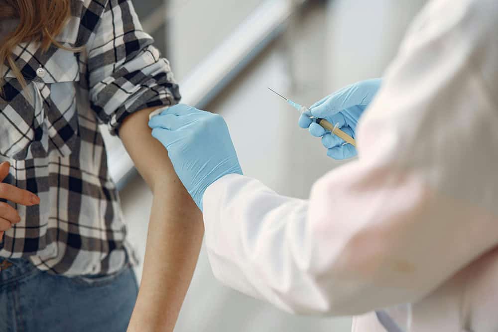 Student receiving vaccination from healthcare professional in university health clinic.