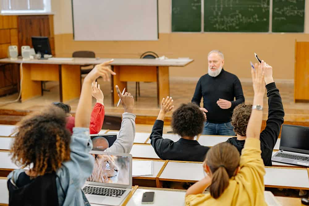 Staff engaging students in a university classroom setting.