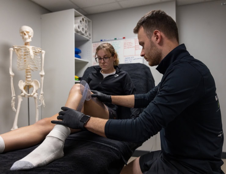 Physiotherapist applying therapy to patient's ankle in a clinical setting.