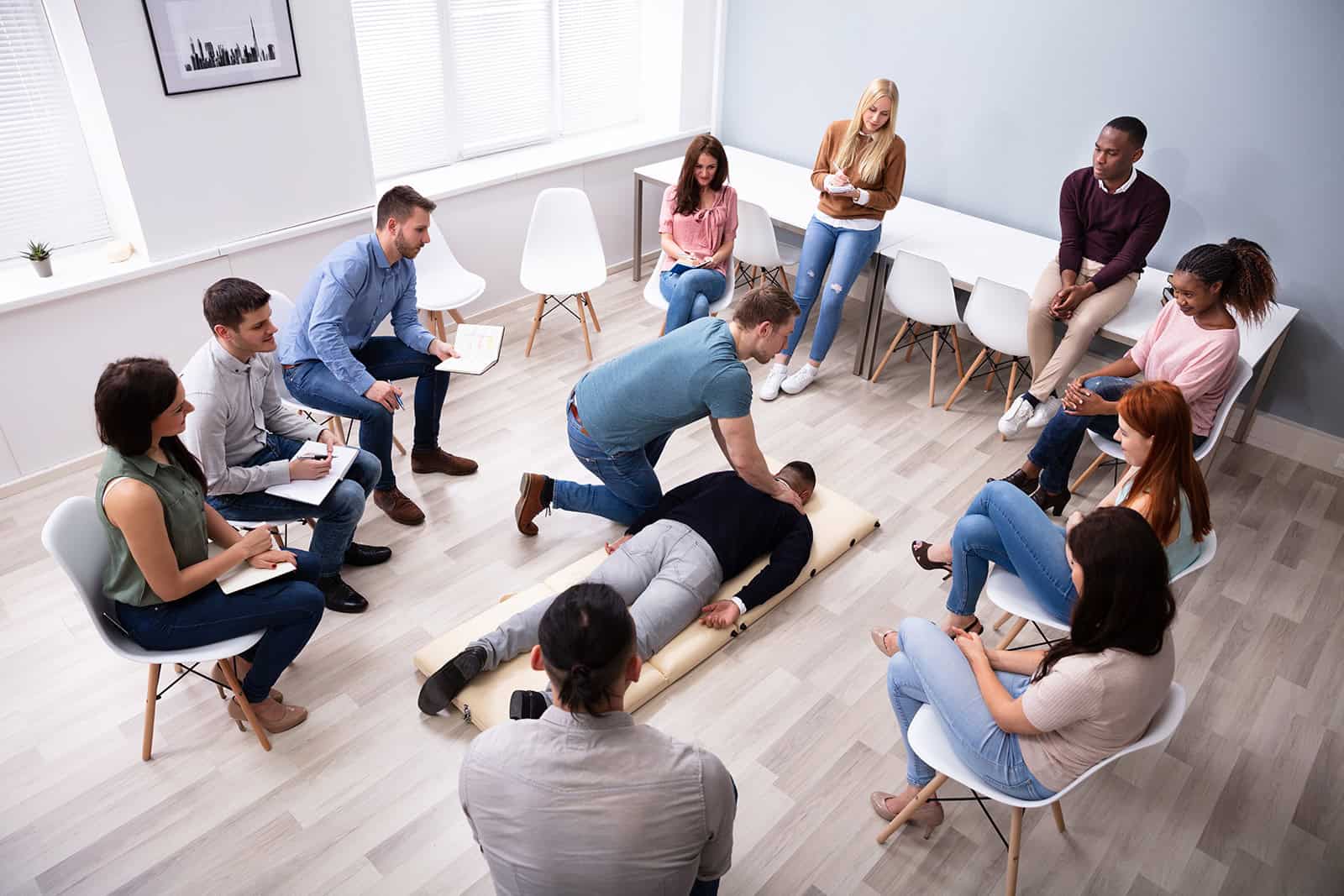 First aid training session with instructor demonstrating CPR techniques to a group of learners.