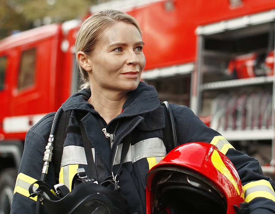 Firefighter with breathing apparatus during air quality testing at fire scene.