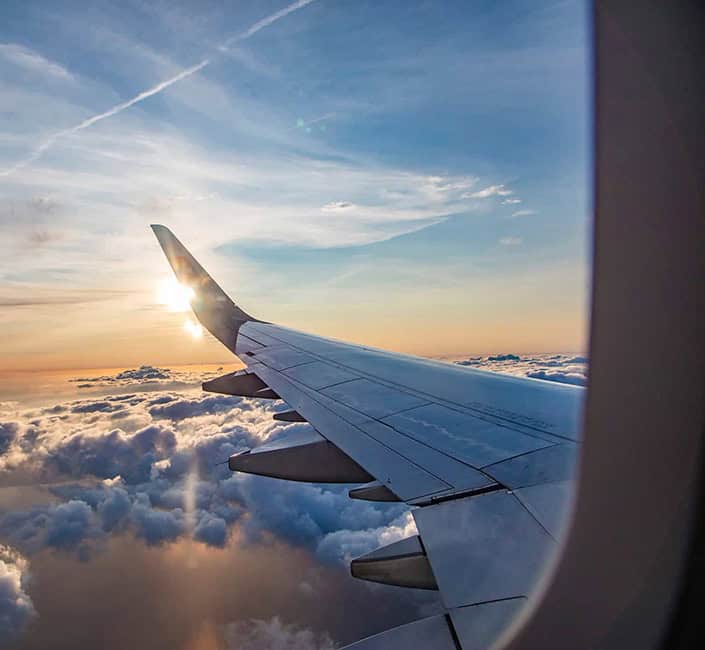 Aircraft wing view during sunset over clouds, capturing the essence of aviation travel.