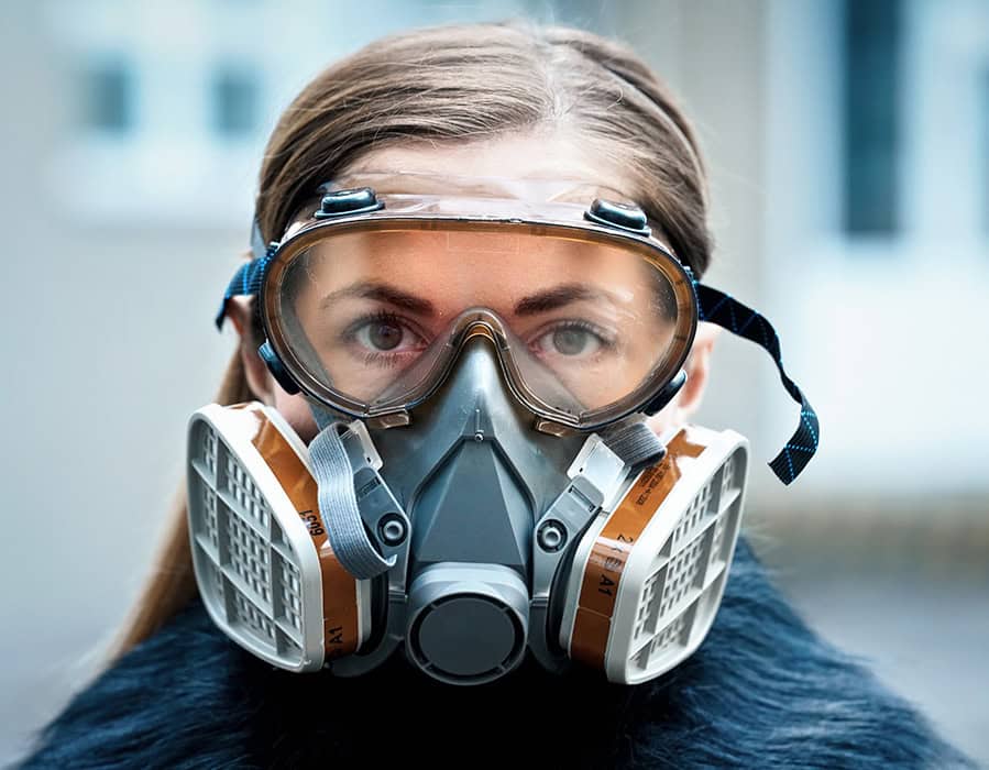 Woman wearing breathing apparatus for air quality testing in industrial environment.
