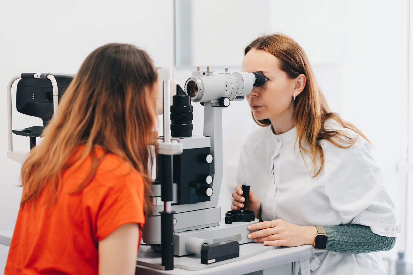 Healthcare professional conducting eye health assessment using slit lamp microscope.