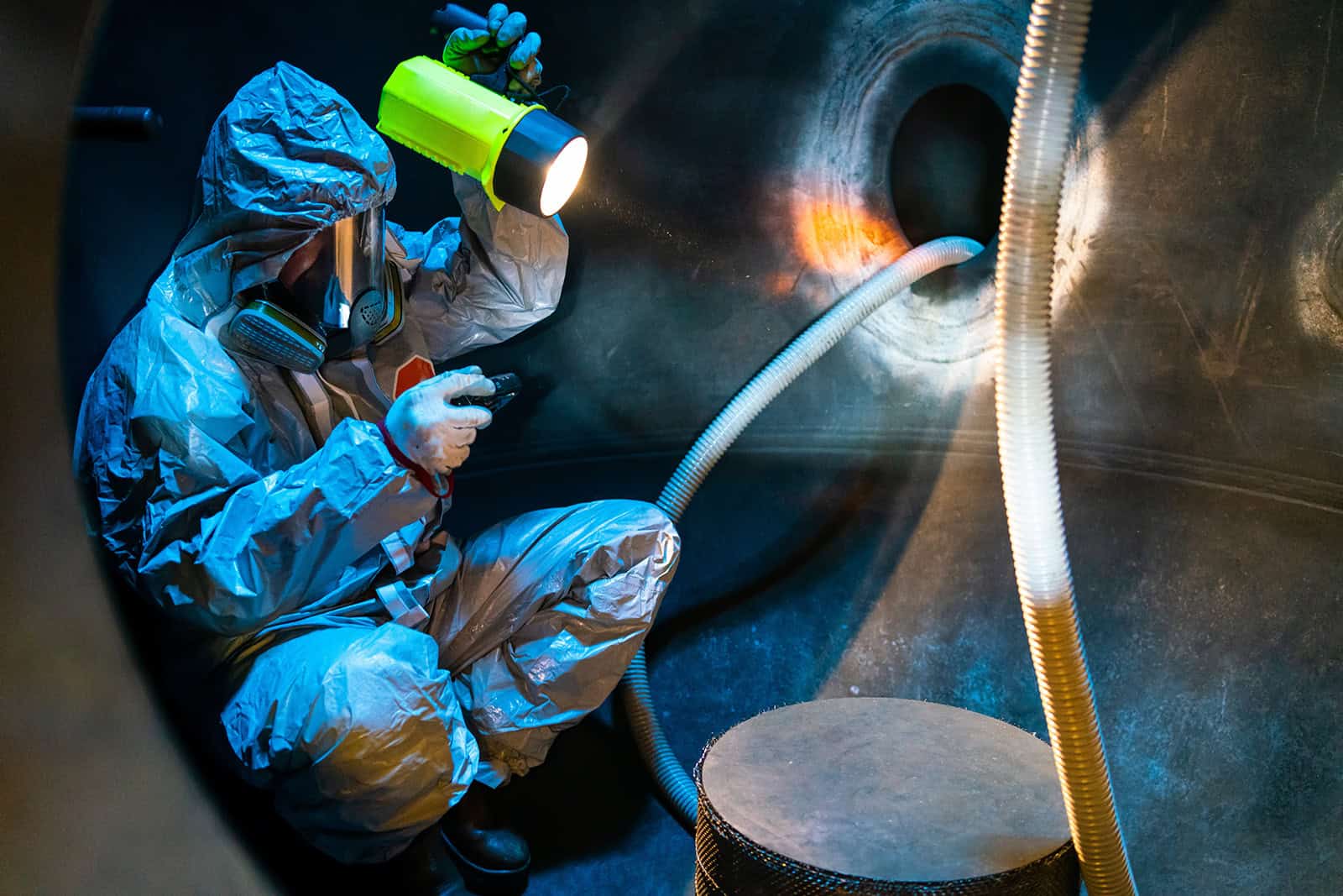 Worker in protective gear performing confined space medical check.