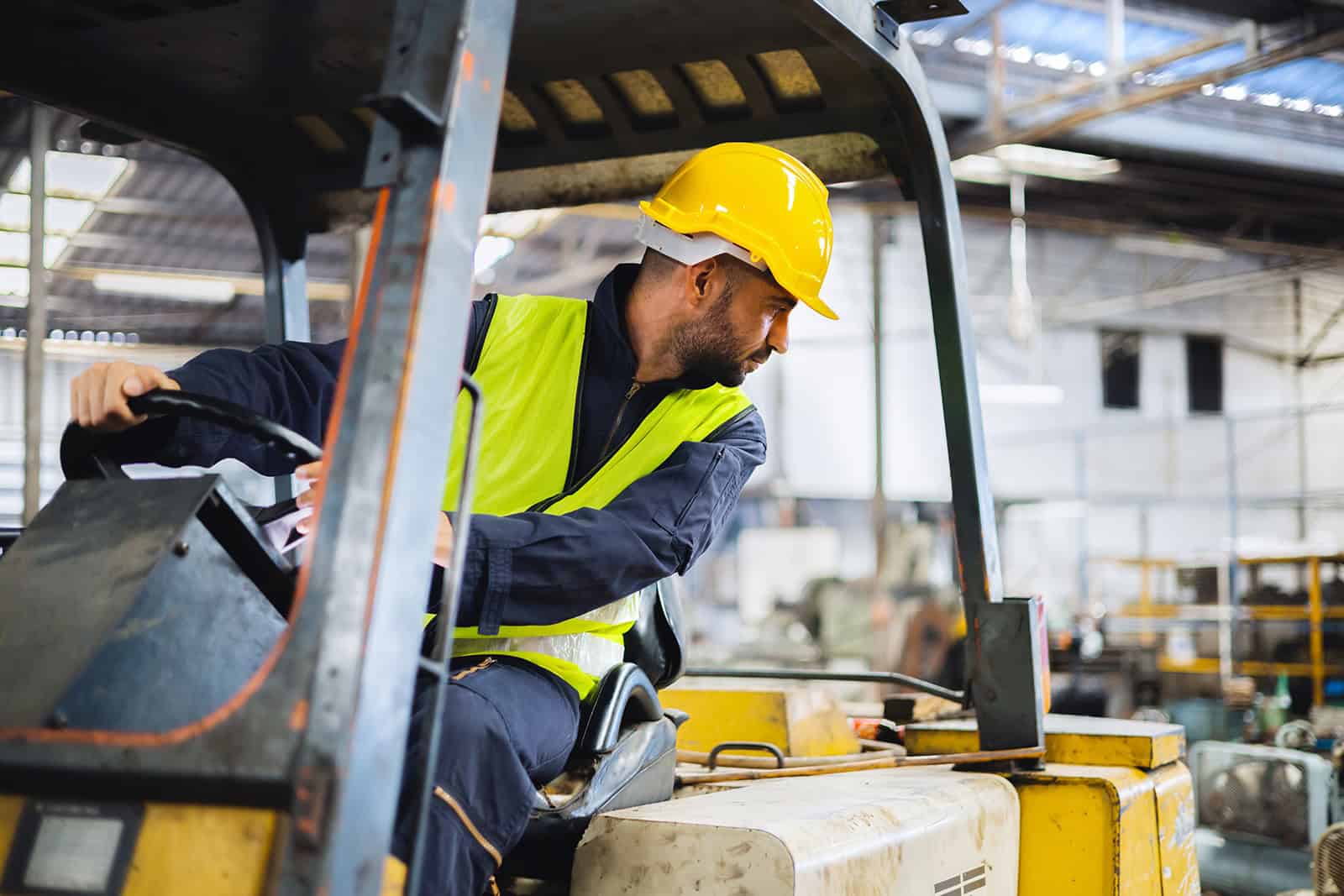 Fork lift truck operator wearing safety gear in a warehouse environment.