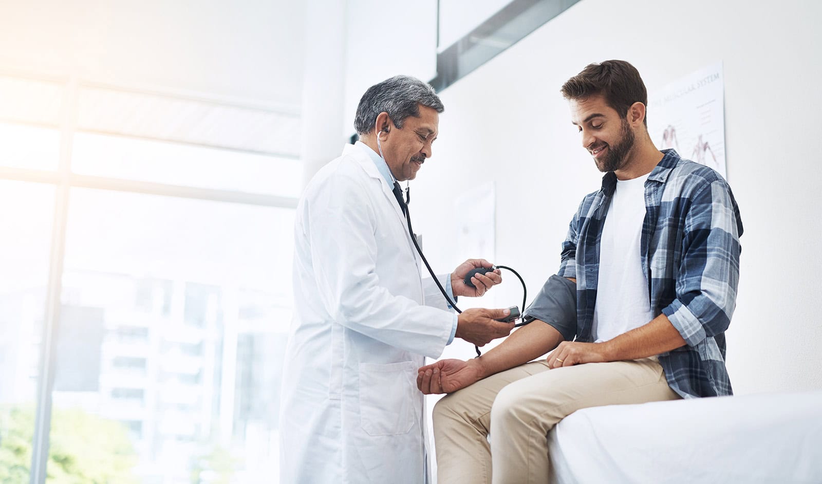 Medical professional measuring blood pressure of a young male patient in a healthcare environment.