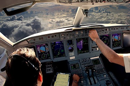 Aviation cockpit with pilots operating modern aircraft instruments and controls in flight.