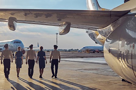 Aircraft ground crew walking near planes at an airport.