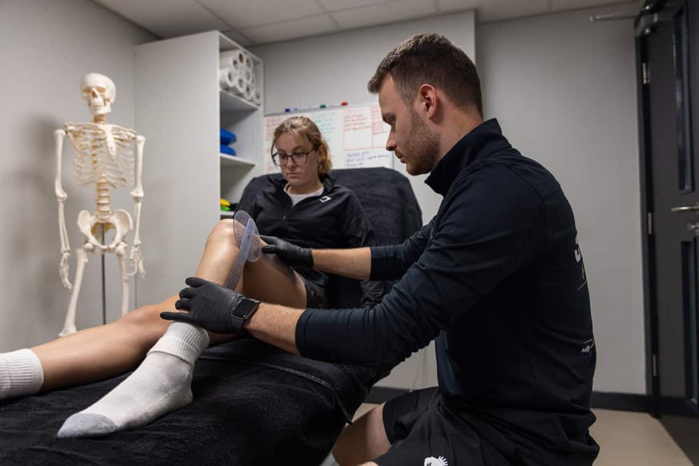 Medical training session demonstrating ankle treatment techniques.