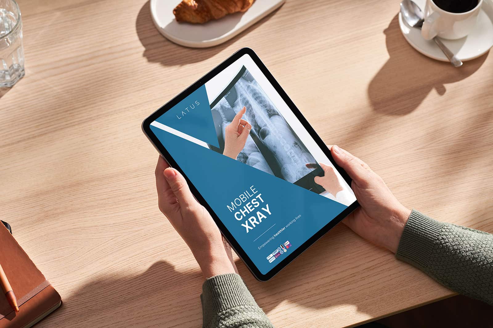 Person viewing a mobile chest X-ray on a tablet device at a desk.