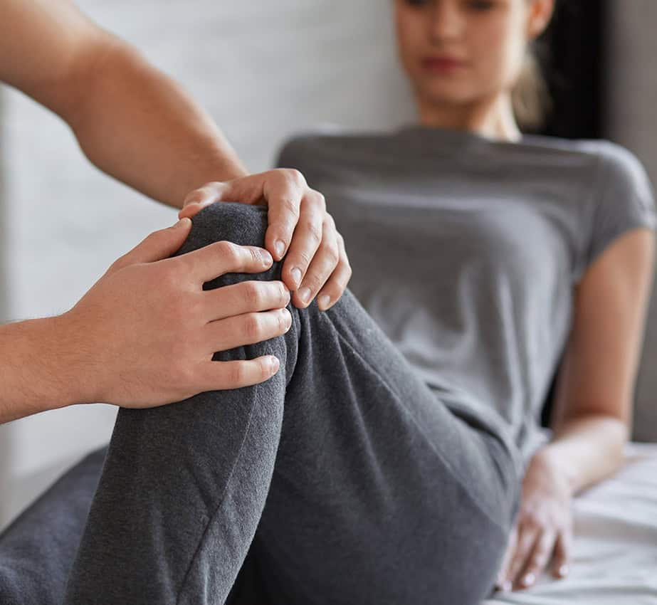 Physiotherapist providing knee therapy to a patient during workplace physiotherapy session.
